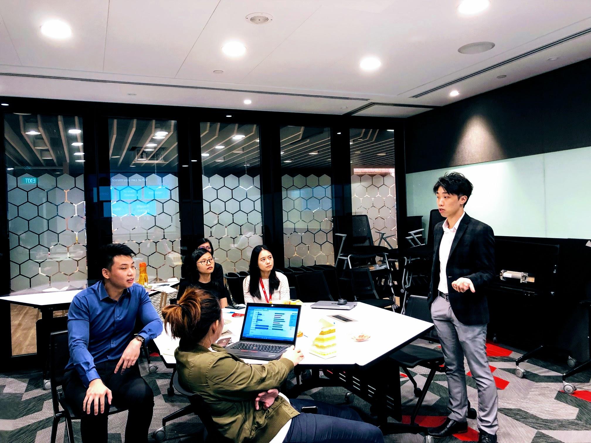 Sam Neo teaching in front of a group during a training session.